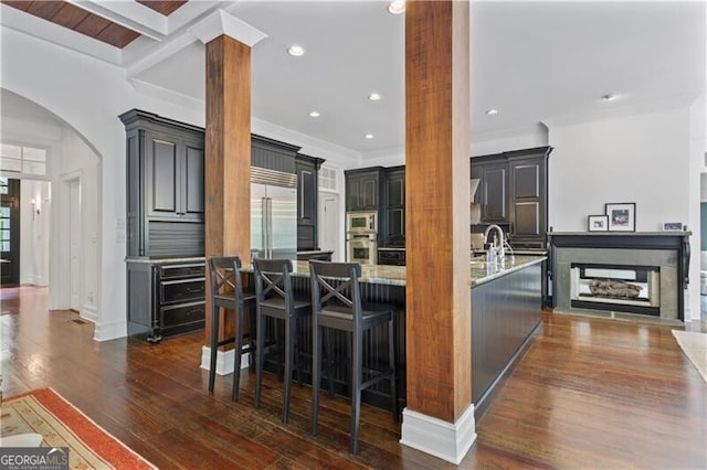 4356 N Buckhead Dr NE, Atlanta, GA 30342 - kitchen featuring built in appliances, dark wood-style flooring, arched walkways, ornamental molding, and a kitchen breakfast bar