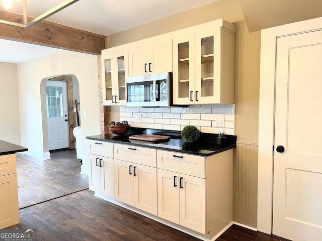 125 Oak Ave, Carrollton, GA 30117 - kitchen with stainless steel microwave, arched walkways, dark countertops, dark wood-style floors, and wainscoting