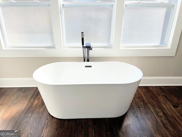 125 Oak Ave, Carrollton, GA 30117 - bathroom view of baseboards, a soaking tub, and wood finished floors