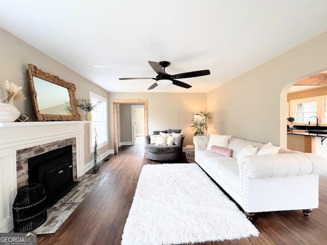 125 Oak Ave, Carrollton, GA 30117 - living room featuring dark wood-style flooring, a ceiling fan, arched walkways, and a fireplace