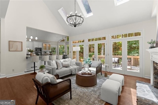 3600 Goldenrod Dr, Alpharetta, GA 30005 - living room with a chandelier, high vaulted ceiling, wood finished floors, a stone fireplace, and a skylight