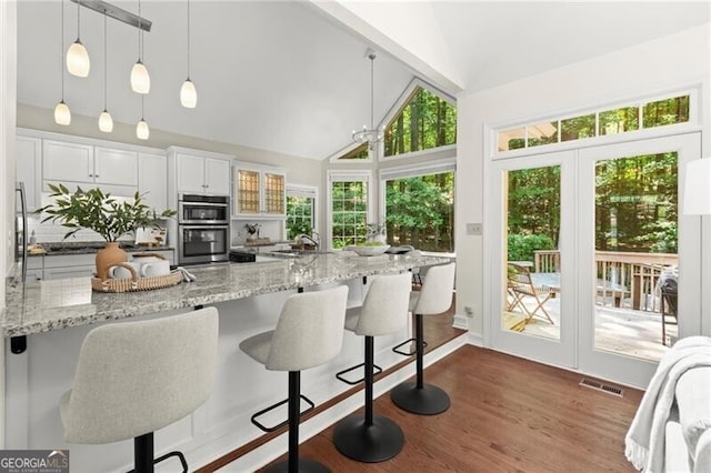 3600 Goldenrod Dr, Alpharetta, GA 30005 - kitchen featuring high vaulted ceiling, a breakfast bar area, stainless steel double oven, white cabinets, and pendant lighting