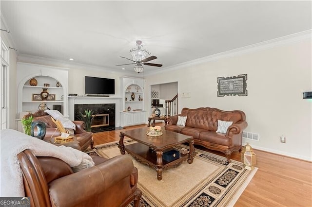 789 Rutland Ct, Lithonia, GA 30058 - living room with a ceiling fan, built in shelves, crown molding, baseboards, and light wood-type flooring