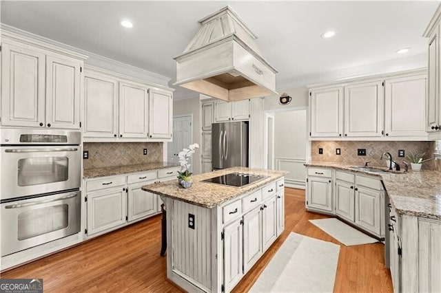 789 Rutland Ct, Lithonia, GA 30058 - kitchen with appliances with stainless steel finishes, a sink, a kitchen island, light wood-style flooring, and tasteful backsplash