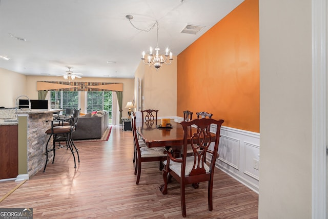 129 Finsbury Ln, Woodstock, GA 30188 - dining room with light wood-type flooring, ceiling fan, a wainscoted wall, and a chandelier