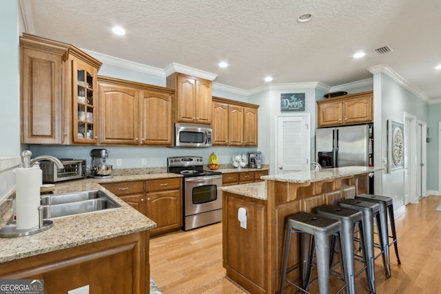247 Laurel Landing Blvd, Kingsland, GA 31548 - kitchen with appliances with stainless steel finishes, a kitchen breakfast bar, brown cabinetry, light wood finished floors, and recessed lighting