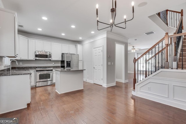 2325 Limehurst Dr NE, Atlanta, GA 30319 - kitchen featuring stainless steel appliances, a center island, ornamental molding, white cabinets, and wood finished floors
