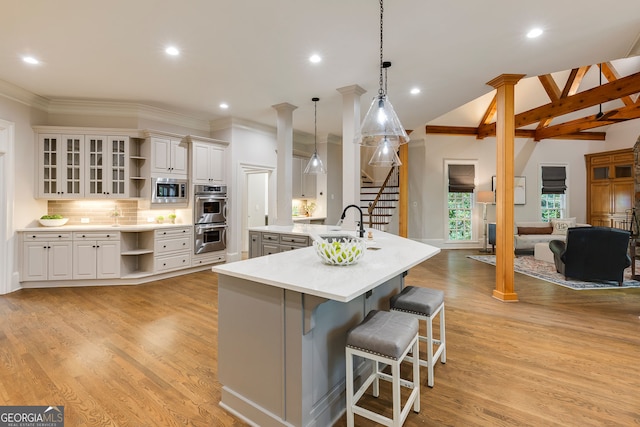 314 Caruso Ct, Sandy Springs, GA 30350 - kitchen featuring open shelves, appliances with stainless steel finishes, a kitchen bar, crown molding, and light wood-type flooring