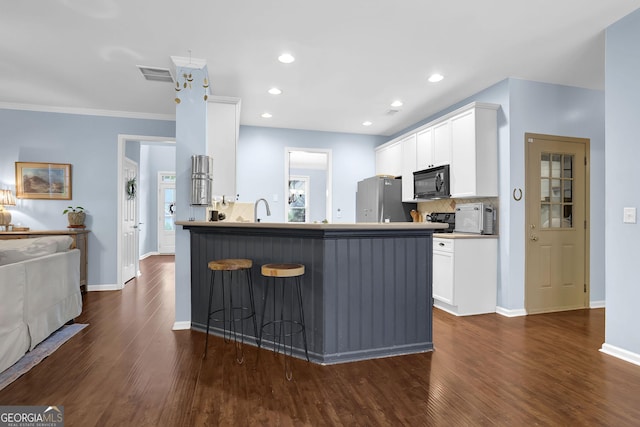 4218 Sandy Branch Dr, Buford, GA 30519 - kitchen with black microwave, freestanding refrigerator, a breakfast bar area, dark wood-style flooring, and white cabinetry