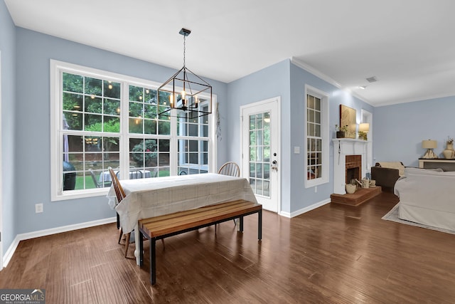 4218 Sandy Branch Dr, Buford, GA 30519 - dining room featuring a chandelier, baseboards, wood finished floors, a fireplace with raised hearth, and ornamental molding