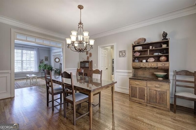 5327 Saville Dr NW, Acworth, GA 30101 - dining space featuring ornamental molding, a chandelier, wood finished floors, wainscoting, and a decorative wall