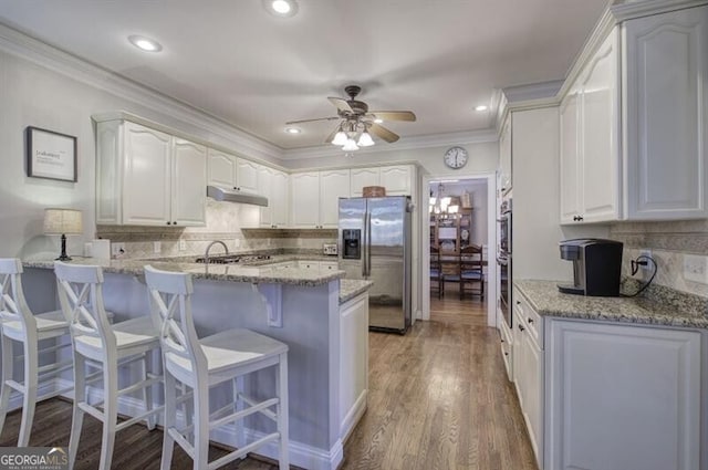 5327 Saville Dr NW, Acworth, GA 30101 - kitchen featuring stainless steel appliances, under cabinet range hood, a peninsula, a kitchen breakfast bar, and decorative backsplash