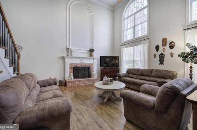 5327 Saville Dr NW, Acworth, GA 30101 - living room featuring a towering ceiling, wood finished floors, stairway, a brick fireplace, and crown molding