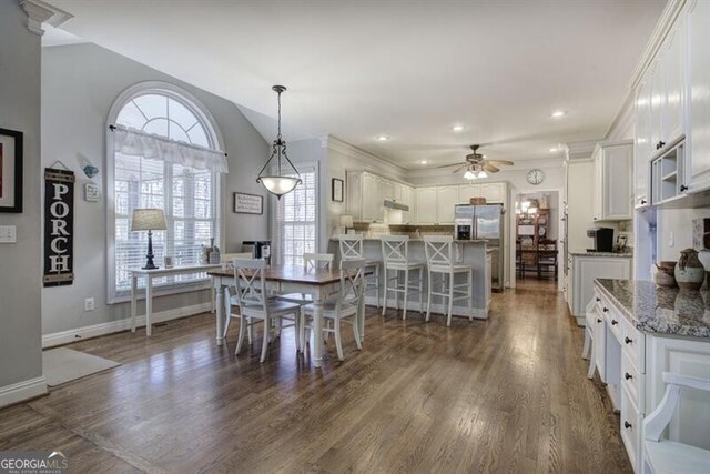 5327 Saville Dr NW, Acworth, GA 30101 - dining space with dark wood finished floors, ceiling fan, lofted ceiling, and crown molding