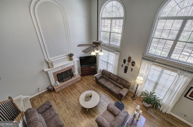 5327 Saville Dr NW, Acworth, GA 30101 - living room featuring a ceiling fan, a brick fireplace, wood finished floors, and a towering ceiling