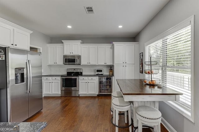 440 S Alexander St, Buford, GA 30518 - kitchen with appliances with stainless steel finishes, wine cooler, dark countertops, decorative backsplash, and white cabinets