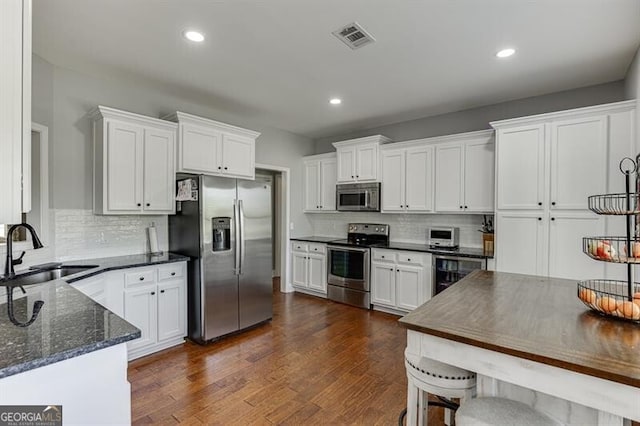 440 S Alexander St, Buford, GA 30518 - kitchen featuring appliances with stainless steel finishes, a sink, wine cooler, tasteful backsplash, and white cabinetry