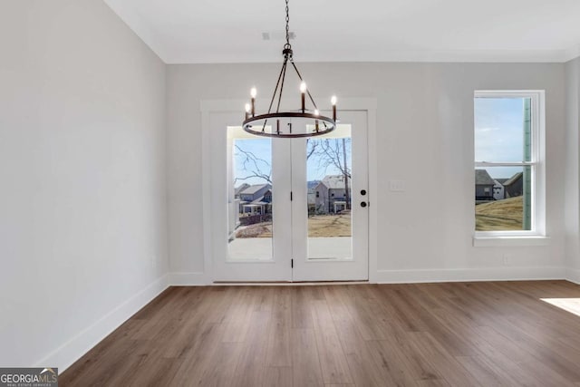 6775 Cambridge Dr, Flowery Branch, GA 30542 - unfurnished dining area featuring a chandelier, wood finished floors, and baseboards