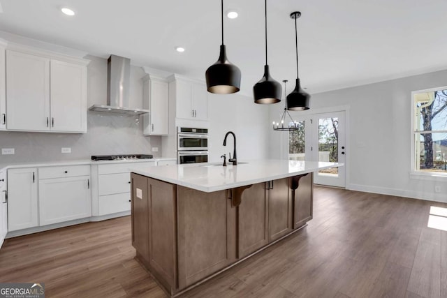6775 Cambridge Dr, Flowery Branch, GA 30542 - kitchen with wall chimney range hood, a sink, stainless steel double oven, healthy amount of natural light, and recessed lighting