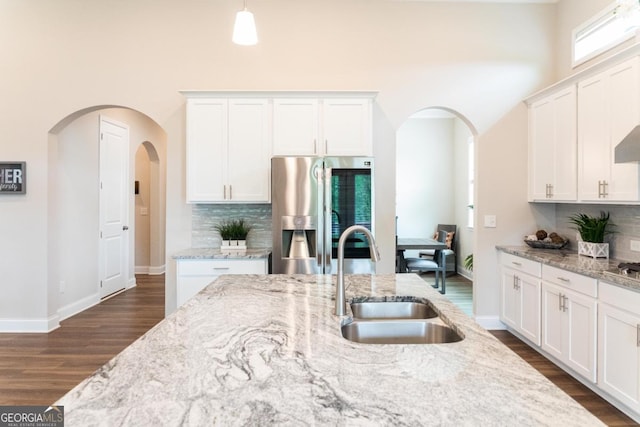 2665 Crowbrook Way, Cumming, GA 30040 - kitchen featuring appliances with stainless steel finishes, arched walkways, dark wood-style floors, decorative backsplash, and a high ceiling