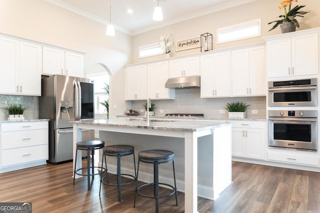 2665 Crowbrook Way, Cumming, GA 30040 - kitchen with under cabinet range hood, appliances with stainless steel finishes, healthy amount of natural light, crown molding, and decorative backsplash