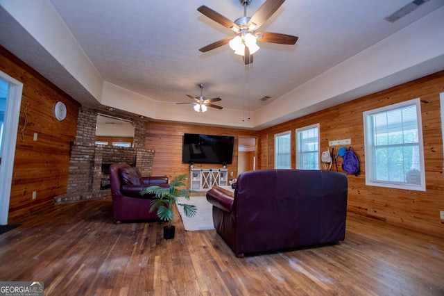 258 Big Oak Rd, Whitesburg, GA 30185 - living room with wood walls, hardwood / wood-style floors, a fireplace, and a ceiling fan