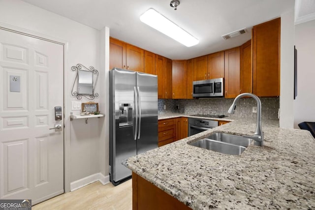 1101 Juniper St NE Unit 1216, Atlanta, GA 30309 - kitchen featuring stainless steel appliances, a sink, brown cabinets, light stone counters, and decorative backsplash