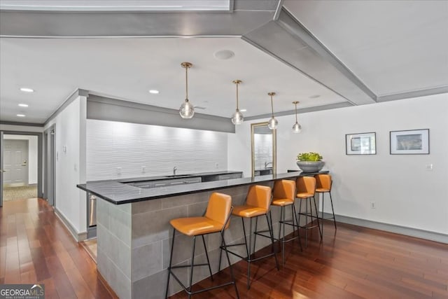 1101 Juniper St NE Unit 1216, Atlanta, GA 30309 - kitchen with hardwood / wood-style flooring, a kitchen bar, dark countertops, baseboards, and recessed lighting