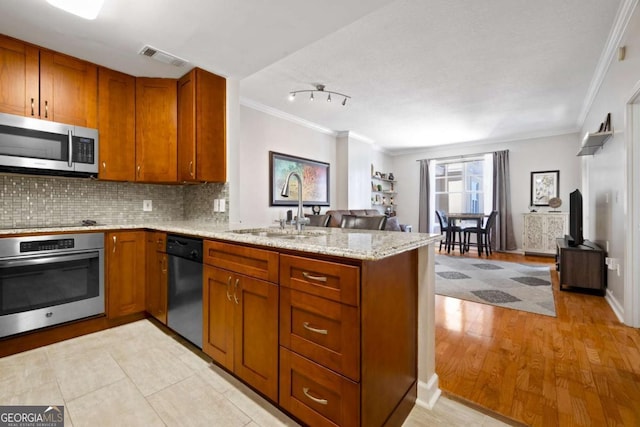 1101 Juniper St NE Unit 1216, Atlanta, GA 30309 - kitchen featuring appliances with stainless steel finishes, a sink, ornamental molding, a peninsula, and brown cabinets