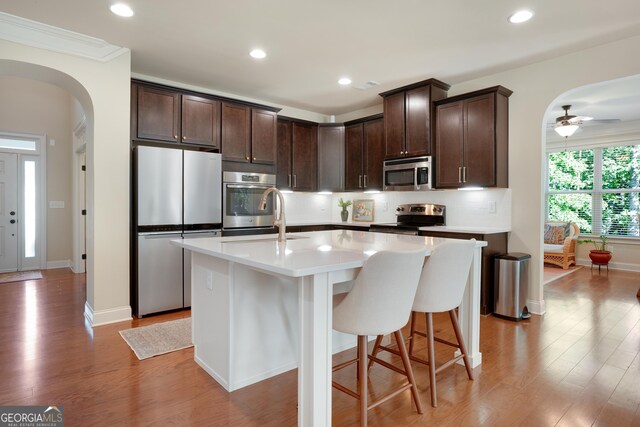 372 Abbington Way, Clarkesville, GA 30523 - kitchen with appliances with stainless steel finishes, dark brown cabinetry, arched walkways, light wood finished floors, and light countertops