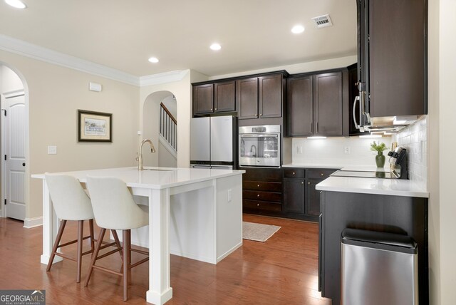 372 Abbington Way, Clarkesville, GA 30523 - kitchen featuring stainless steel appliances, a sink, arched walkways, crown molding, and backsplash