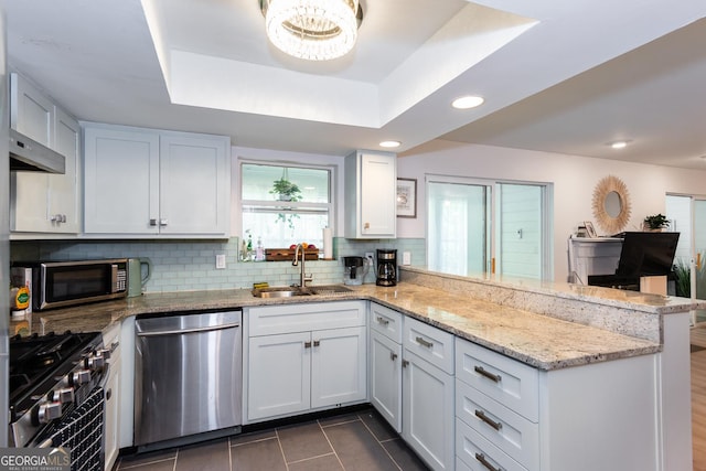 72 Sutton Pl, Avondale Estates, GA 30002 - kitchen featuring stainless steel appliances, a peninsula, a sink, tasteful backsplash, and dark tile patterned floors