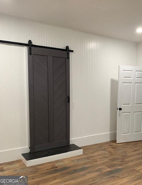 3827 Avant Rd, Blackshear, GA 31516 - detailed view of baseboards, a barn door, and wood finished floors