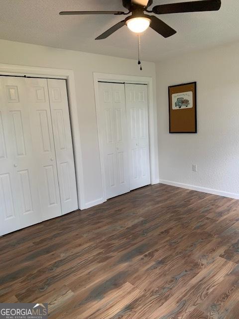 3827 Avant Rd, Blackshear, GA 31516 - unfurnished bedroom with multiple closets, baseboards, dark wood finished floors, and a ceiling fan