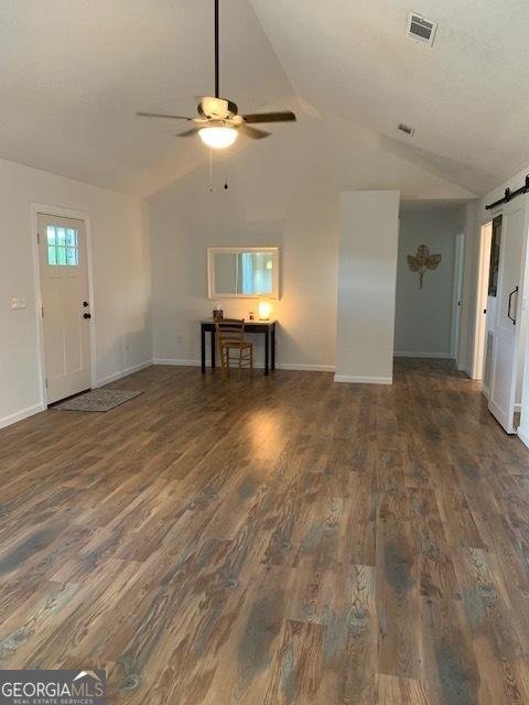 3827 Avant Rd, Blackshear, GA 31516 - unfurnished living room with a barn door, wood finished floors, ceiling fan, vaulted ceiling, and baseboards