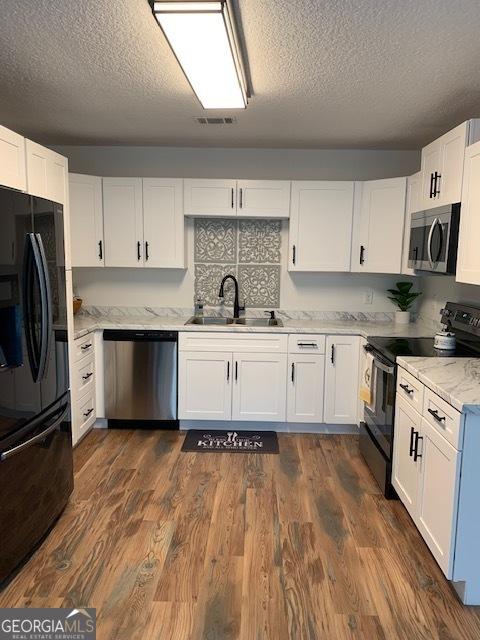 3827 Avant Rd, Blackshear, GA 31516 - kitchen with black appliances, a sink, a textured ceiling, and white cabinets