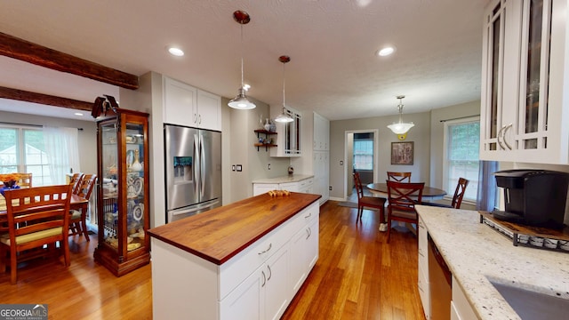 2884 Overwood Ln, Snellville, GA 30078 - kitchen with stainless steel refrigerator with ice dispenser, wood counters, light wood-type flooring, white cabinets, and decorative light fixtures