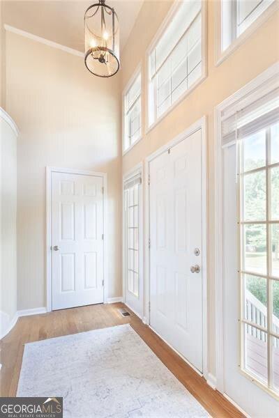 2577 Abbotts Glen Dr NW, Acworth, GA 30101 - entryway with a high ceiling, wood finished floors, a chandelier, and crown molding