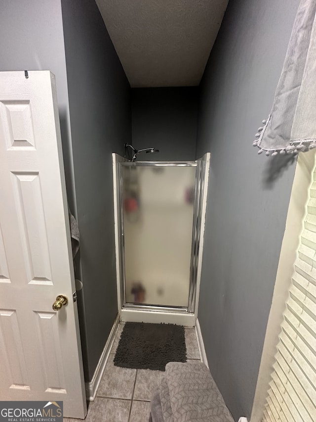 65 Barclay Ct, Newnan, GA 30263 - bathroom featuring a stall shower, tile patterned flooring, baseboards, and a textured ceiling