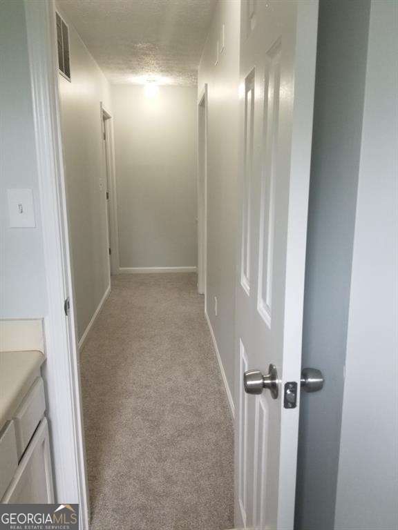 3530 Hopkins Ct, Powder Springs, GA 30127 - corridor featuring light carpet, baseboards, and a textured ceiling