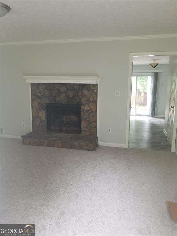 3530 Hopkins Ct, Powder Springs, GA 30127 - unfurnished living room with ornamental molding, baseboards, carpet floors, a stone fireplace, and a textured ceiling
