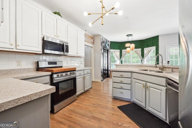 4630 Smokestone Dr, Douglasville, GA 30135 - kitchen featuring appliances with stainless steel finishes, a sink, gray cabinets, a chandelier, and backsplash