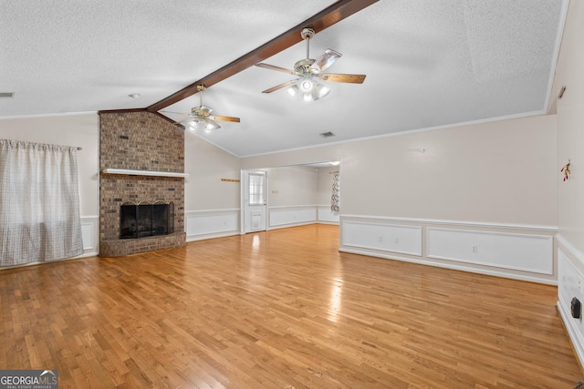 1206 Zittrouer Rd, Guyton, GA 31312 - unfurnished living room with a ceiling fan, light wood-type flooring, a textured ceiling, a fireplace, and a wainscoted wall