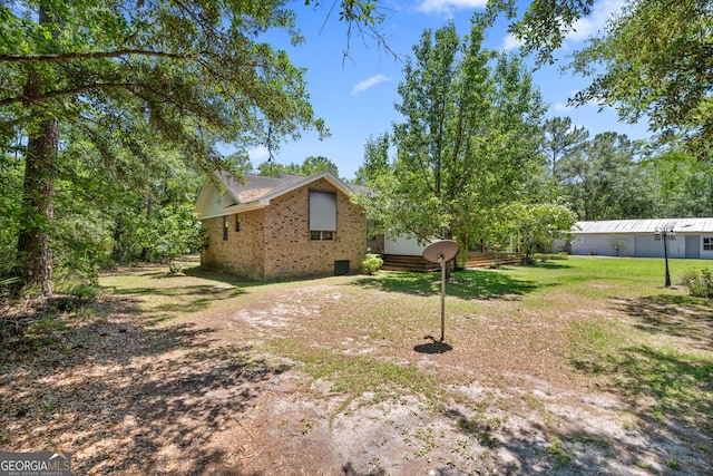 1206 Zittrouer Rd, Guyton, GA 31312 - view of side of home featuring brick siding, a lawn, and a wooden deck