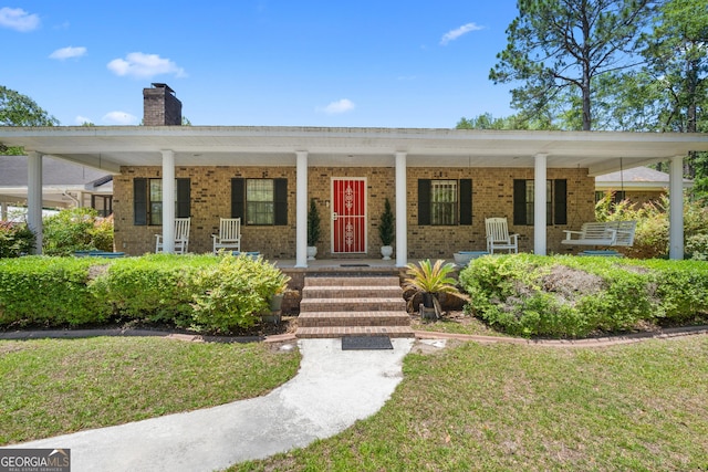 1206 Zittrouer Rd, Guyton, GA 31312 - view of front of house featuring a chimney, covered porch, brick siding, and a front lawn