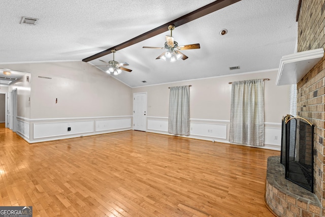 1206 Zittrouer Rd, Guyton, GA 31312 - unfurnished living room featuring a brick fireplace, light wood-style floors, a ceiling fan, a textured ceiling, and wainscoting
