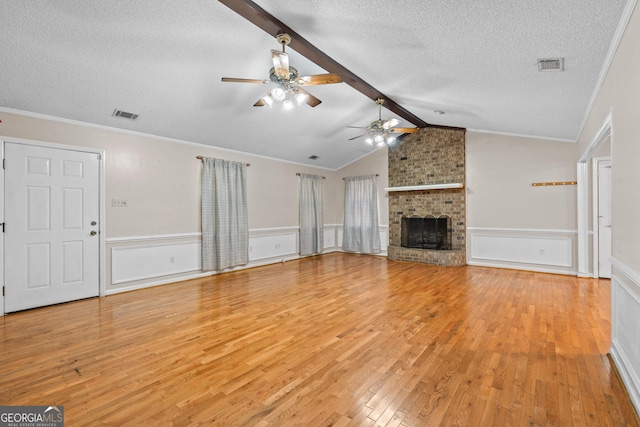 1206 Zittrouer Rd, Guyton, GA 31312 - unfurnished living room with a textured ceiling, ceiling fan, light wood finished floors, a brick fireplace, and wainscoting