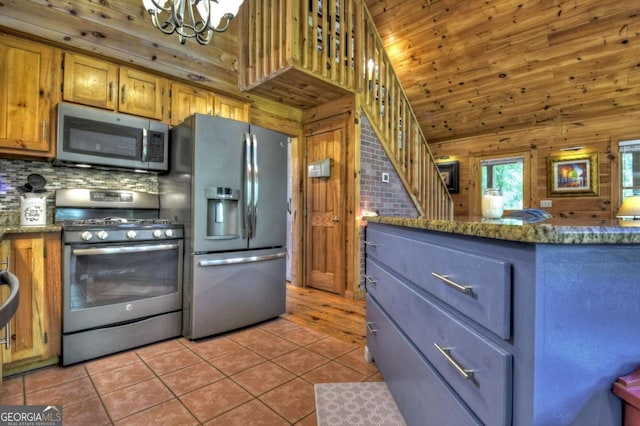 241 Dunn Mill Creek Rd, Blue Ridge, GA 30513 - kitchen with stainless steel appliances, a chandelier, light tile patterned flooring, wood walls, and dark stone countertops