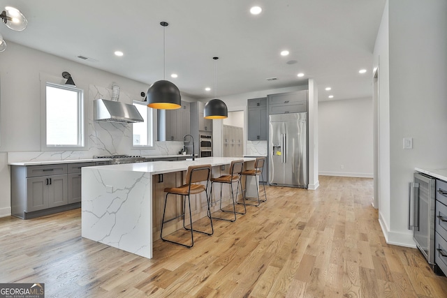 1240 Hayes Sq, Peachtree City, GA 30269 - kitchen featuring appliances with stainless steel finishes, gray cabinetry, beverage cooler, backsplash, and an island with sink