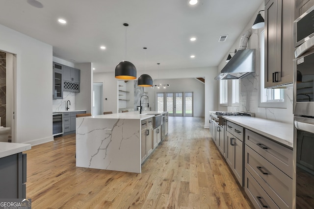 1240 Hayes Sq, Peachtree City, GA 30269 - kitchen featuring gray cabinetry, light wood finished floors, tasteful backsplash, a large island with sink, and recessed lighting